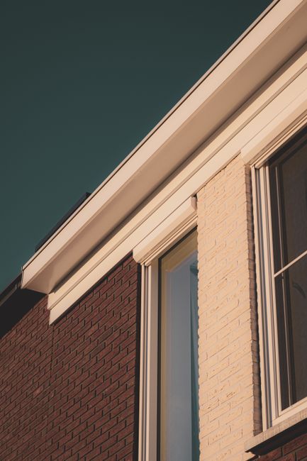 Close-up view of a modern house exterior showcasing contrasting brick and cream walls with windows.