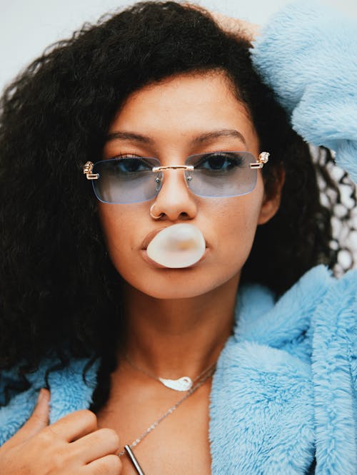 Curly hair fashion model blowing chewing gum
