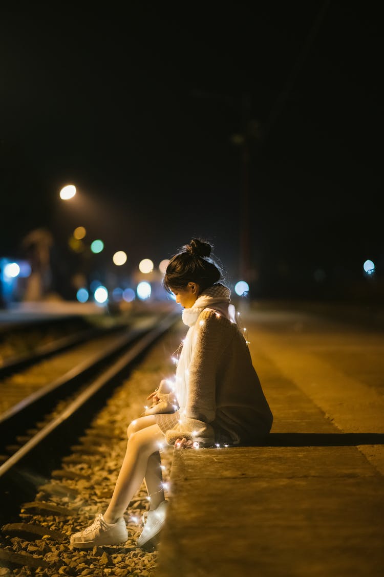 Woman Sitting On Edge By Railway Track At Night