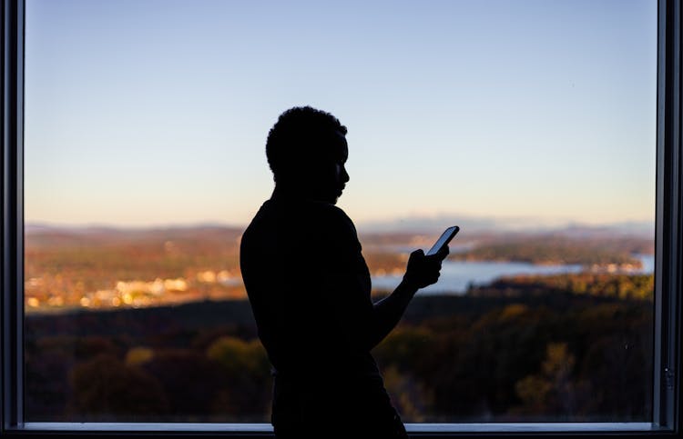 Person Looking At Phone With Landscape In The Background