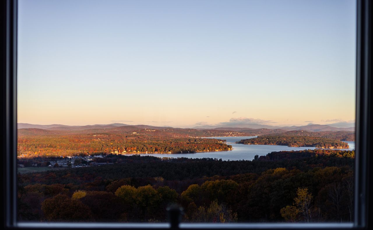 a peaceful sunset view of a lake and hills framed by autumn foliage