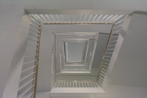 Low Angle Shot of a White Staircase in a Tall Building 