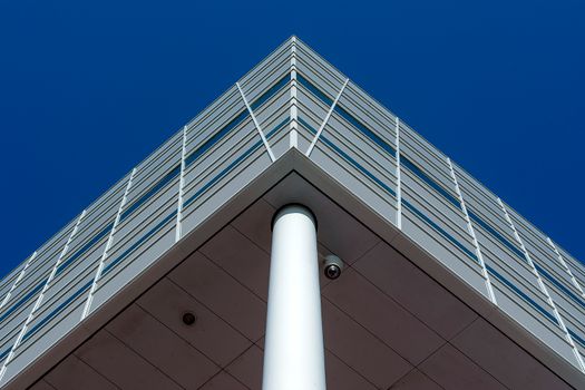 Low angle view of a modern building facade against a clear blue sky.