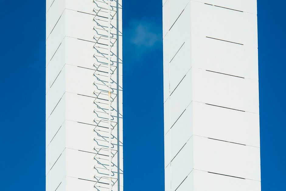Close-up of white architectural towers with exterior ladder against a vivid blue sky.