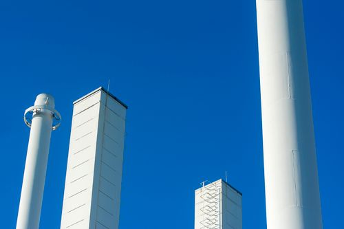 Free Low angle view of modern white chimneys set against a clear blue sky, showcasing contemporary industrial architecture. Stock Photo