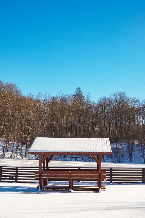 Free A serene winter scene with a snow-covered picnic table under a clear blue sky. Stock Photo