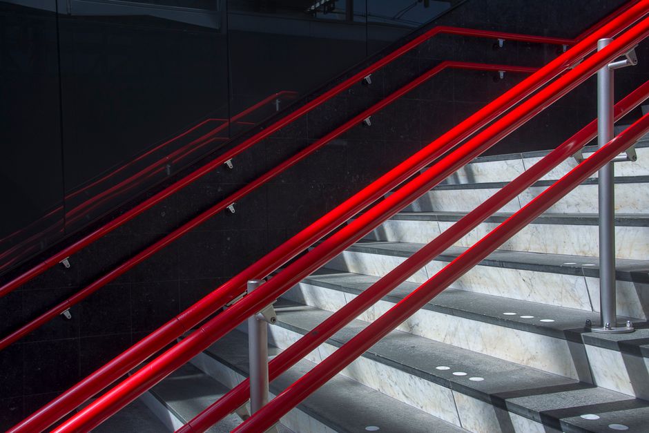 Contemporary staircase with striking red handrails in an urban setting.