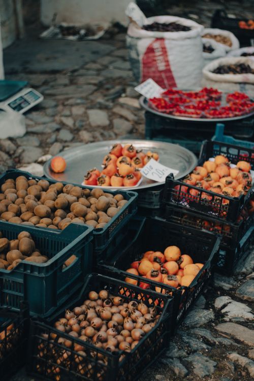 Free Vibrant assortment of fruits like persimmons and kiwis at an outdoor market. Stock Photo