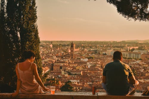 Back View of People Sitting on a Wall with a Panoramic View of Verona, Italy 