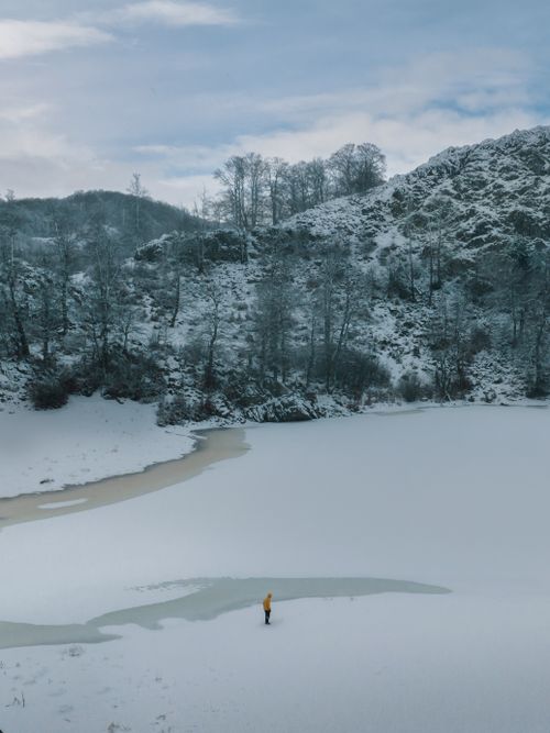 Free A serene winter landscape featuring a snow-covered hill and a frozen lake in Albania. Stock Photo