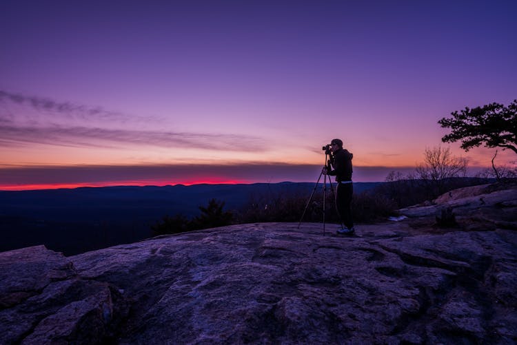 Man Taking A Photo Using Camera With Tripod