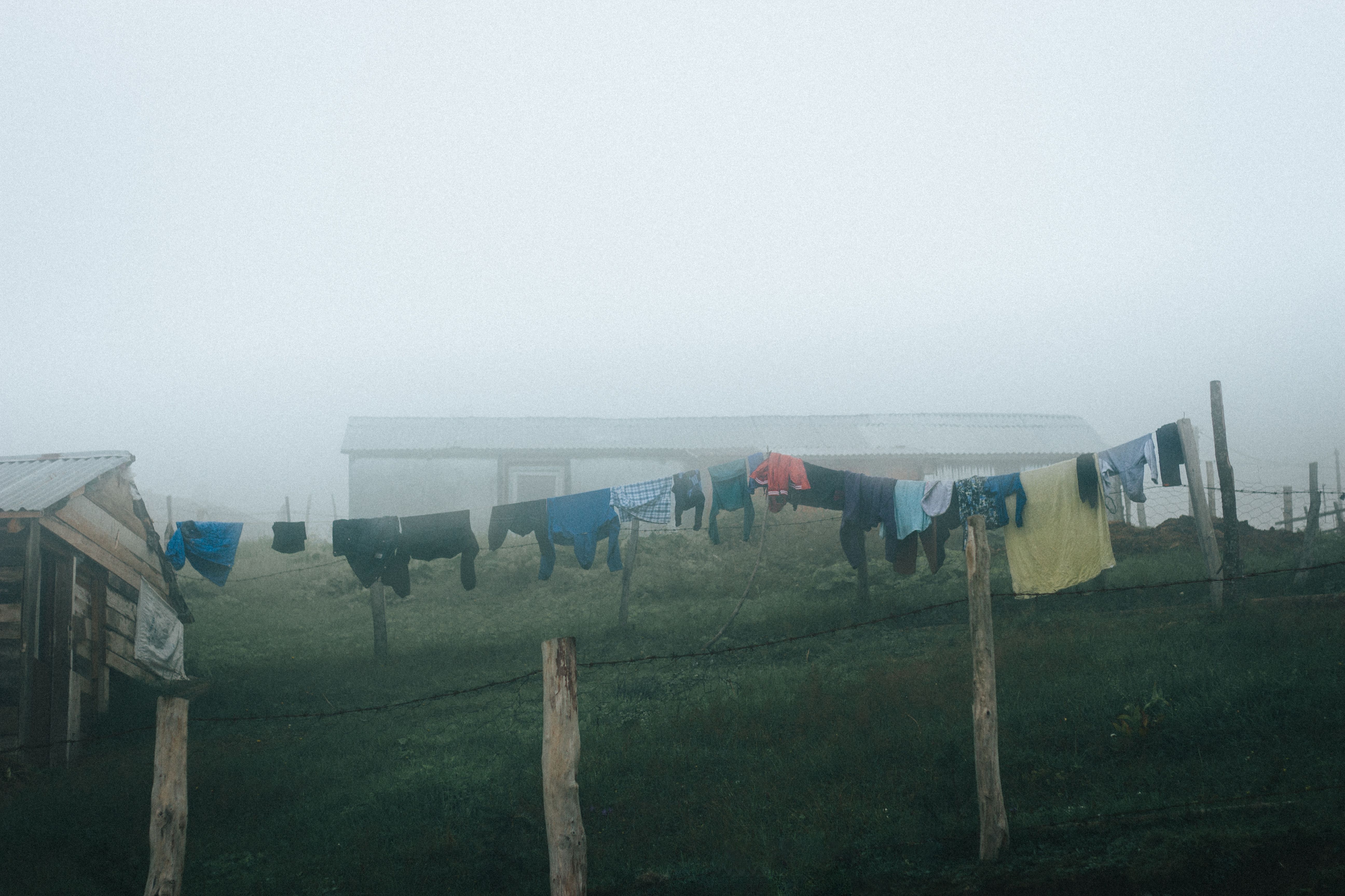 Clothes drying on a line in a misty rural setting, evoking a peaceful countryside mood.