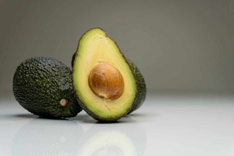 7 Best Calorie Counting Apps for Weight Loss (Compared) Close-up of ripe avocados with a sliced half showing the seed, against a gray background.