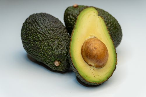 Free Close-up view of a ripe avocado halved, revealing its seed against a smooth background. Stock Photo