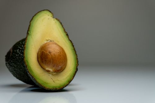 Free Half avocado on gray background, showcasing fresh green and brown hues for food photography. Stock Photo