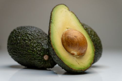 Free Close-up of fresh avocado halves against a gray background, highlighting their texture. Stock Photo