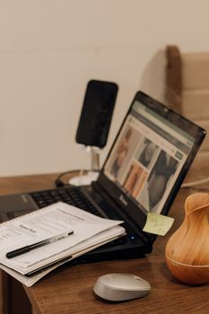 A home office setup with a laptop, notepad, and vase on a wooden desk.