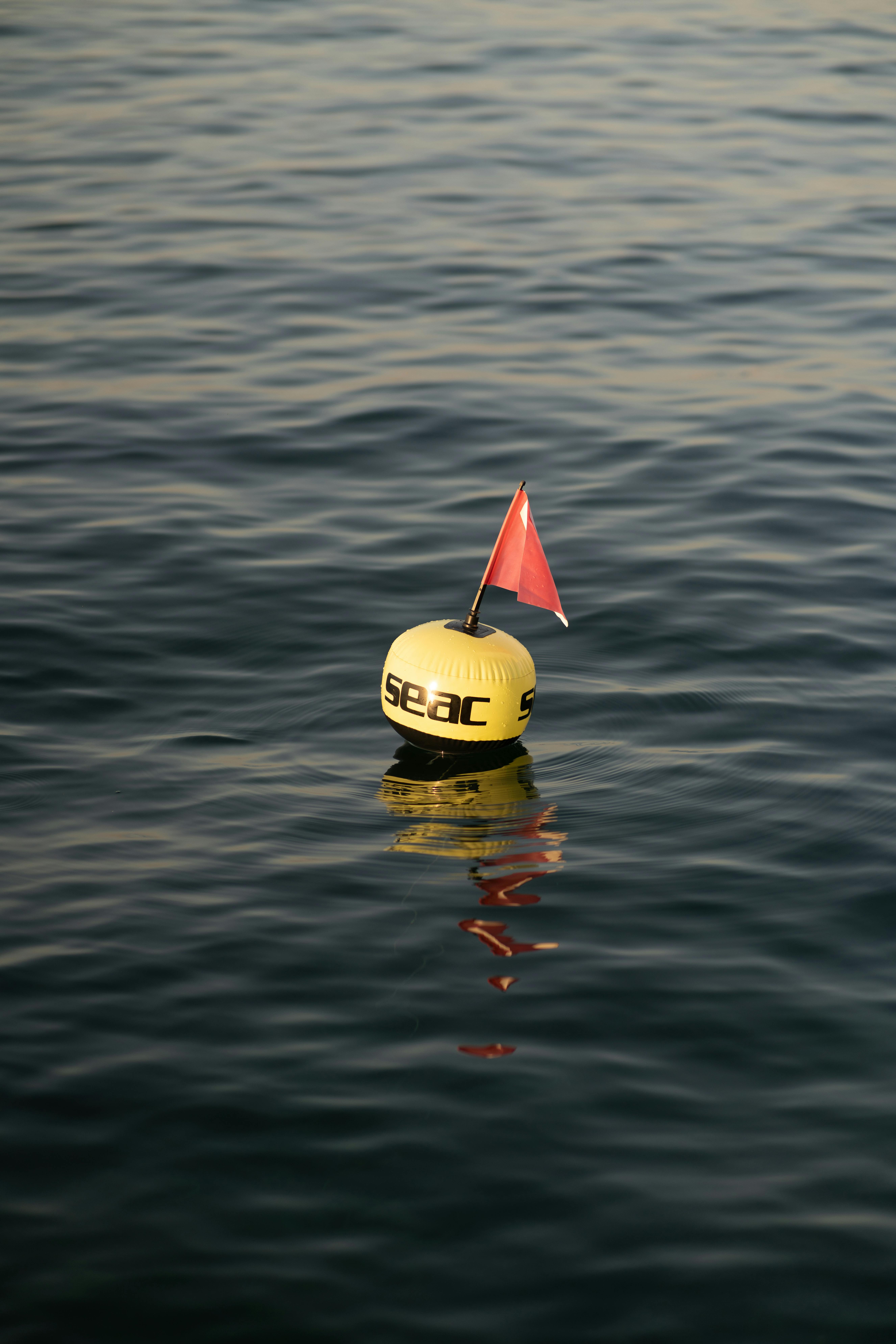 Yellow Buoy With Flag For Fishing Net Between The Blue Waves Of