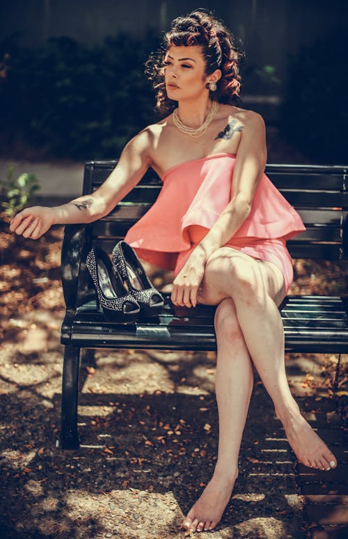 Barefoot Woman in Pink Dress Sitting on Bench