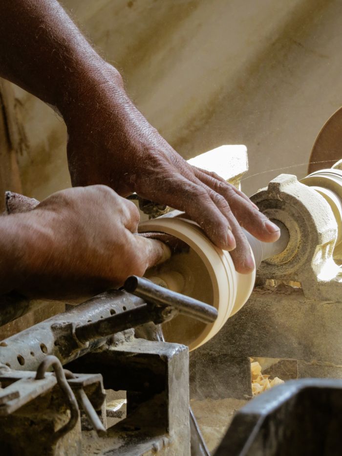 Hands turning a wooden handle on a lathe