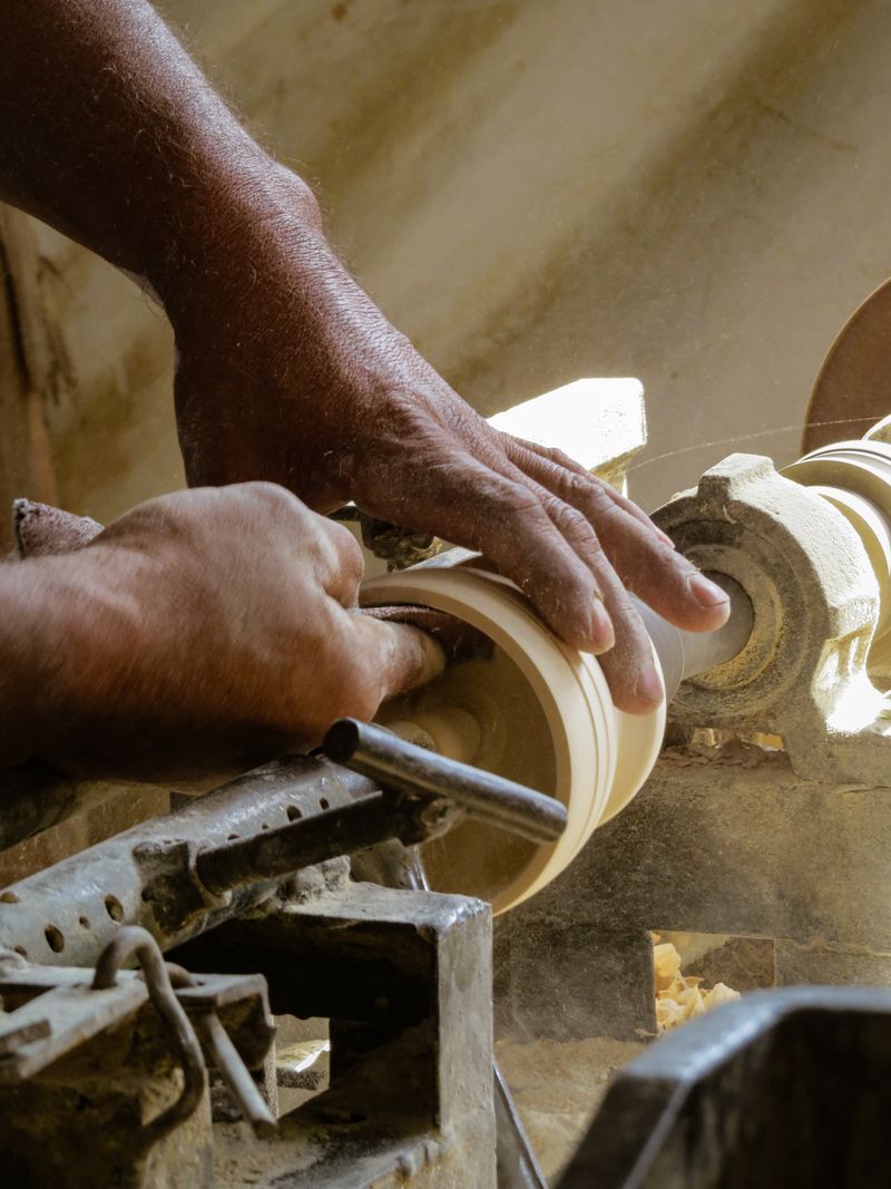 Hands turning a wooden handle on a lathe