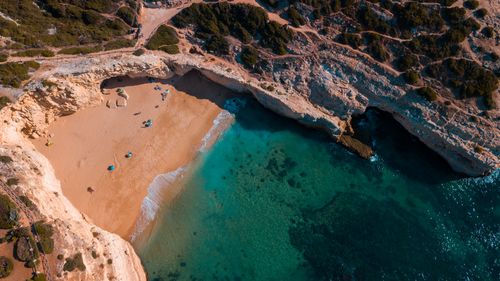 Free Stunning aerial shot of a secluded beach with golden sand and turquoise waters, surrounded by rocky cliffs. Stock Photo