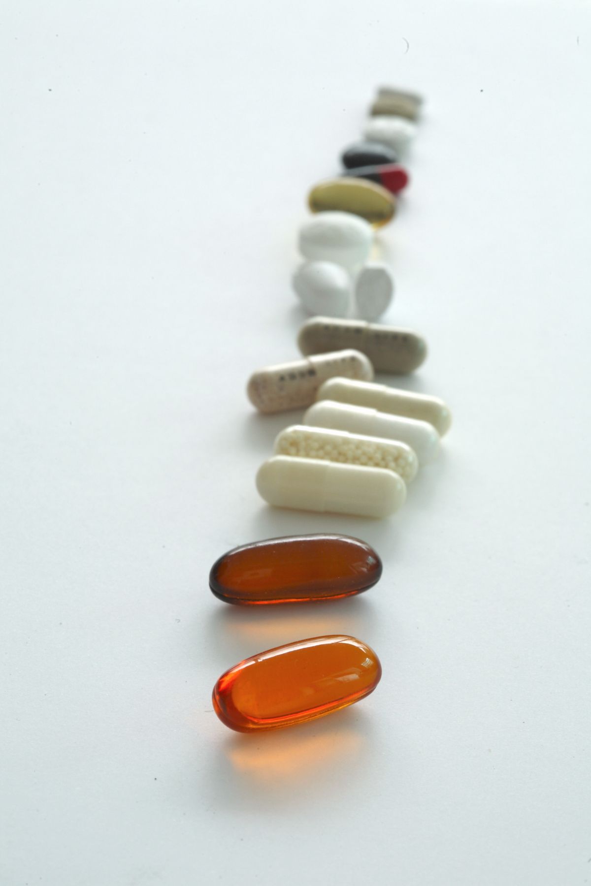 A line of different tablets and capsules laid out in sequence