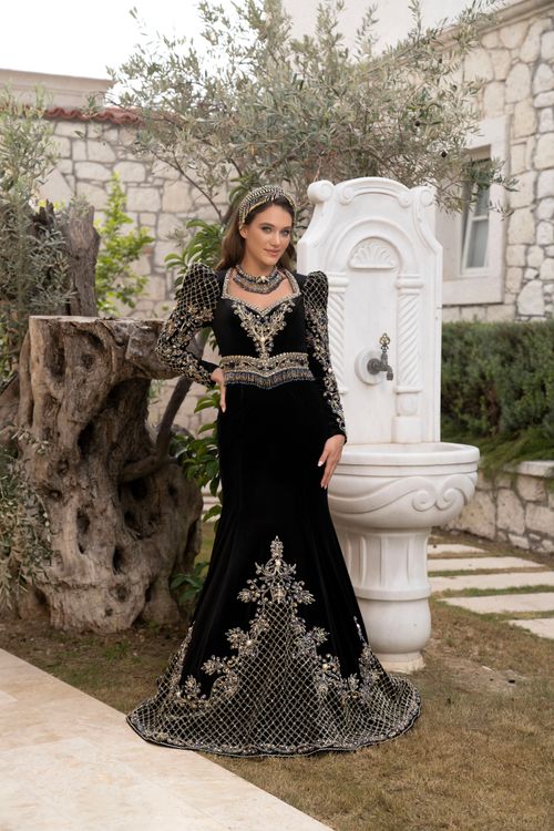 Free A beautiful bride in a traditional embellished caftan poses outdoors by a stone fountain in İzmir, Türkiye. Stock Photo