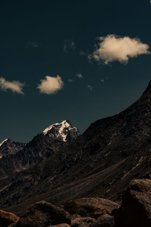 Free Majestic mountains under a deep blue sky with striking clouds, showcasing nature's grandeur. Stock Photo