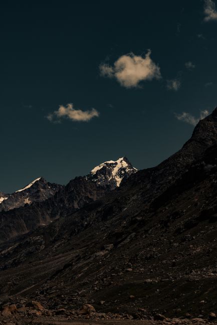 Stunning mountain landscape showcasing rocky slopes and snowy peaks under a vibrant sky.