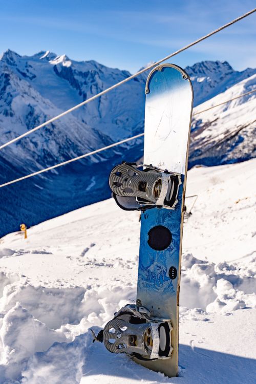Free A snowboard embedded in snow against a stunning winter mountain backdrop. Stock Photo