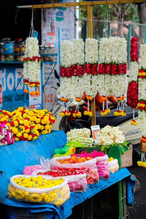 Free A colorful display of fresh flower garlands and bouquets at a bustling outdoor market stall. Stock Photo