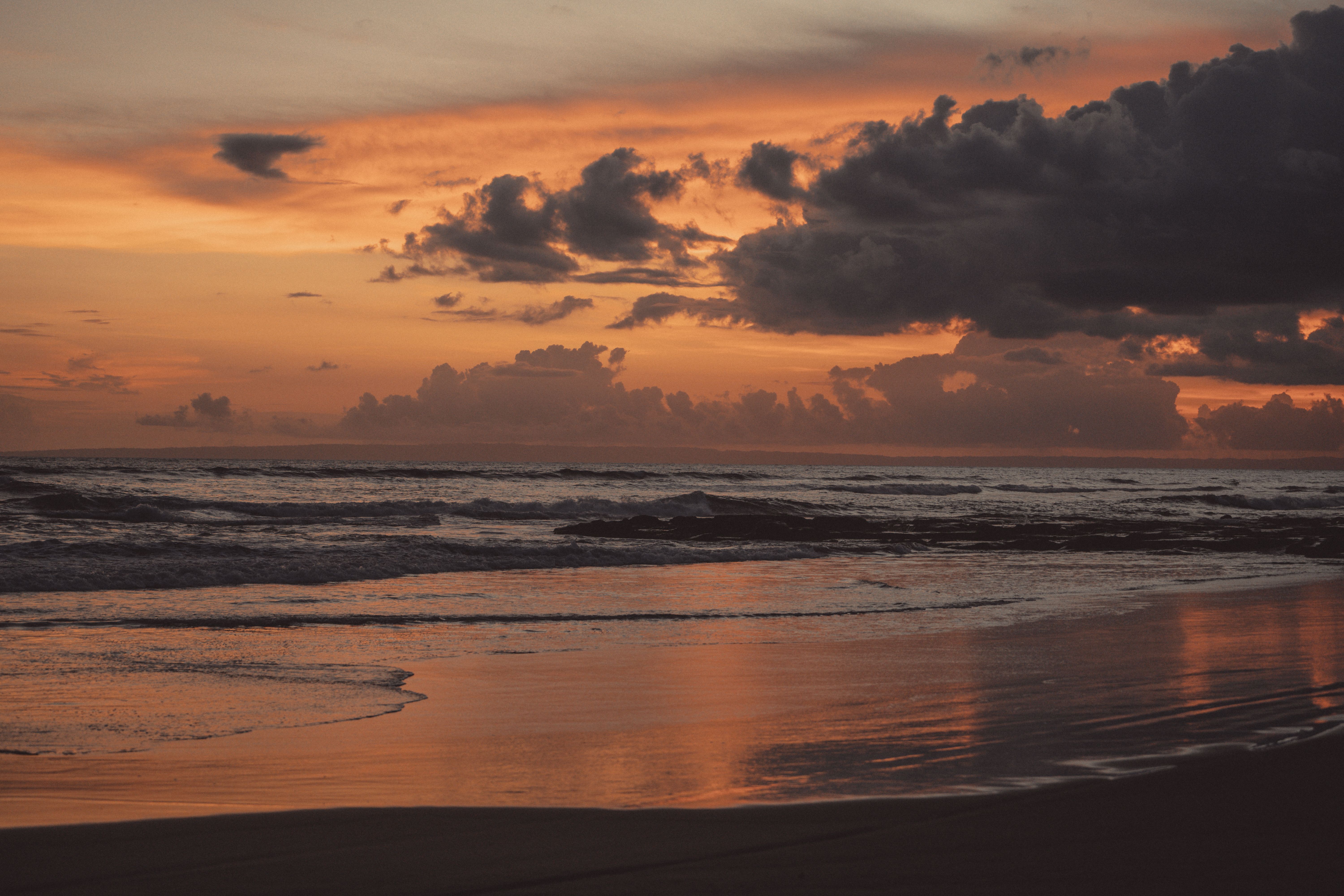 A sunset on the beach with clouds and water · Free Stock Photo