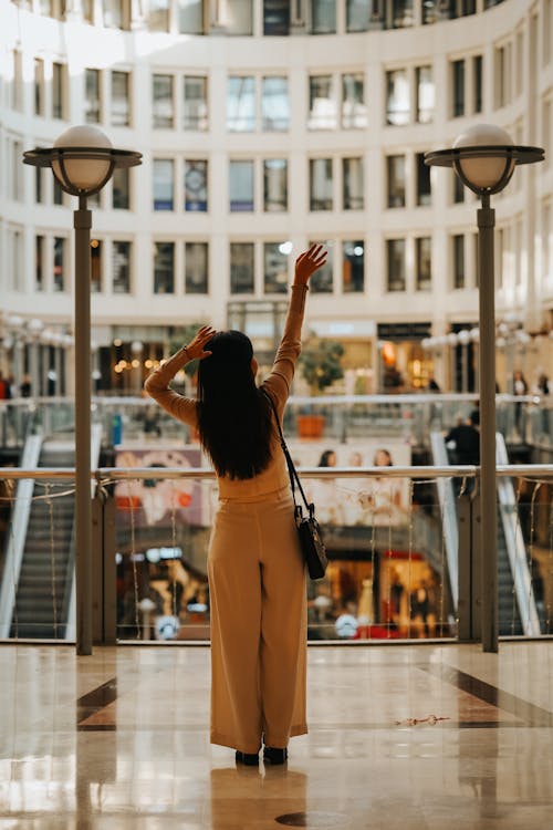Woman Standing with Arms Raised at Shopping Mall