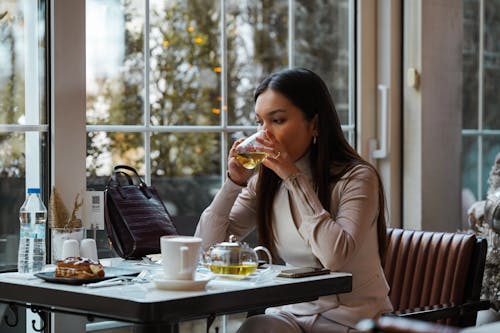 Woman Sitting at Cafe and Drinking
