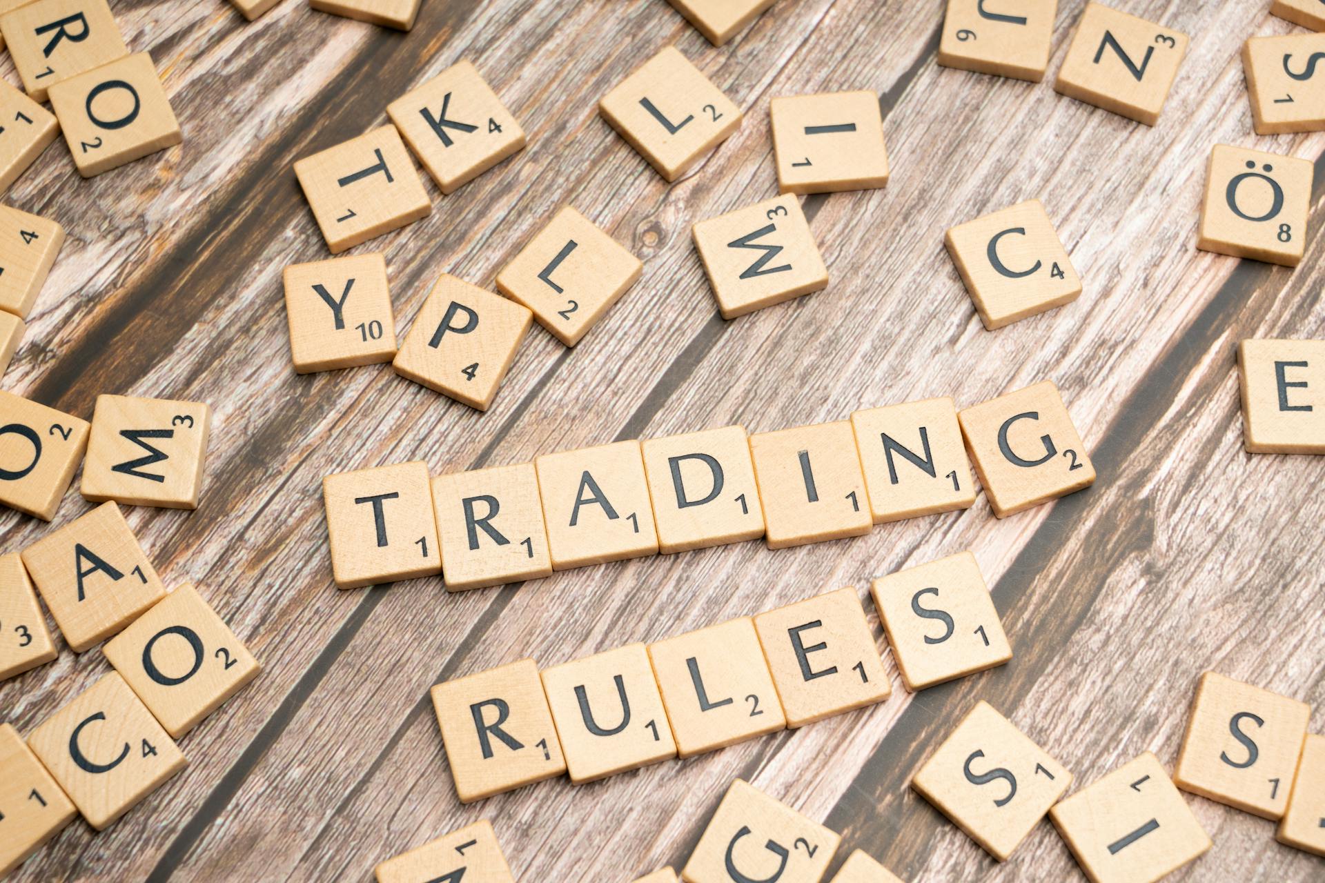 Wooden letter tiles arranged to spell 'Trading Rules' on a wooden surface.