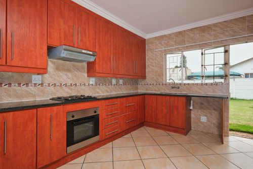 Free Spacious modern kitchen with wooden cabinets and sleek countertops in a sunny space. Stock Photo