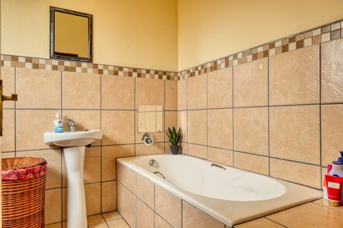 Free Elegant bathroom interior with beige tiles, bathtub, and modern basin. Stock Photo