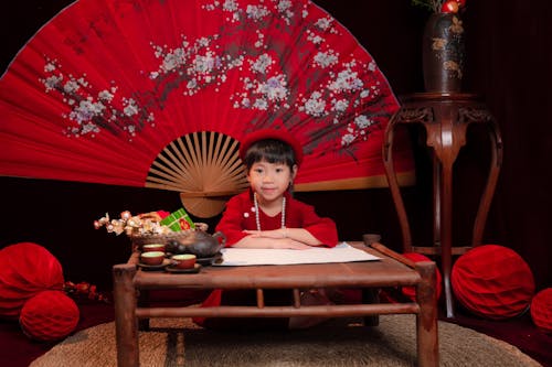 Girl Sitting in Traditional Clothing by Table