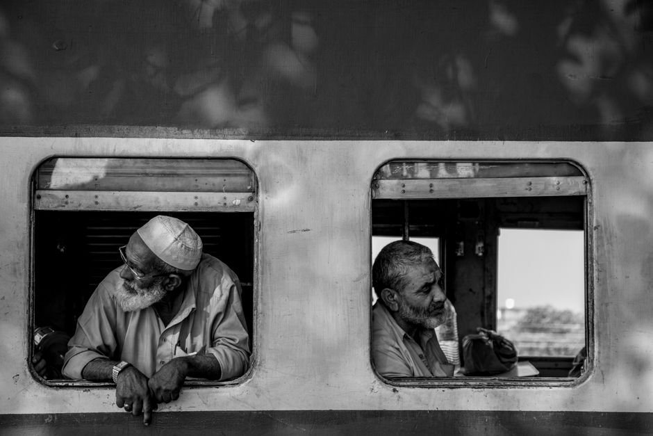 Elderly men on a train journey, gazing through open windows in Islamabad.