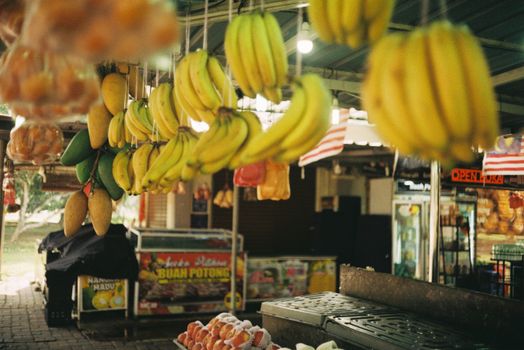Hanging variety of fruits at a vibrant outdoor market in Temerloh, Malaysia.