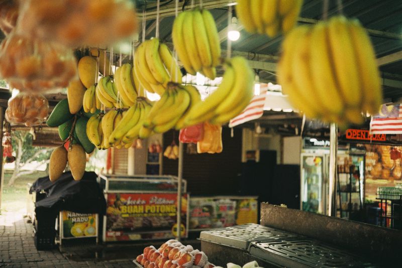 Hanging variety of fruits at a vibrant outdoor market in Temerloh, Malaysia.
