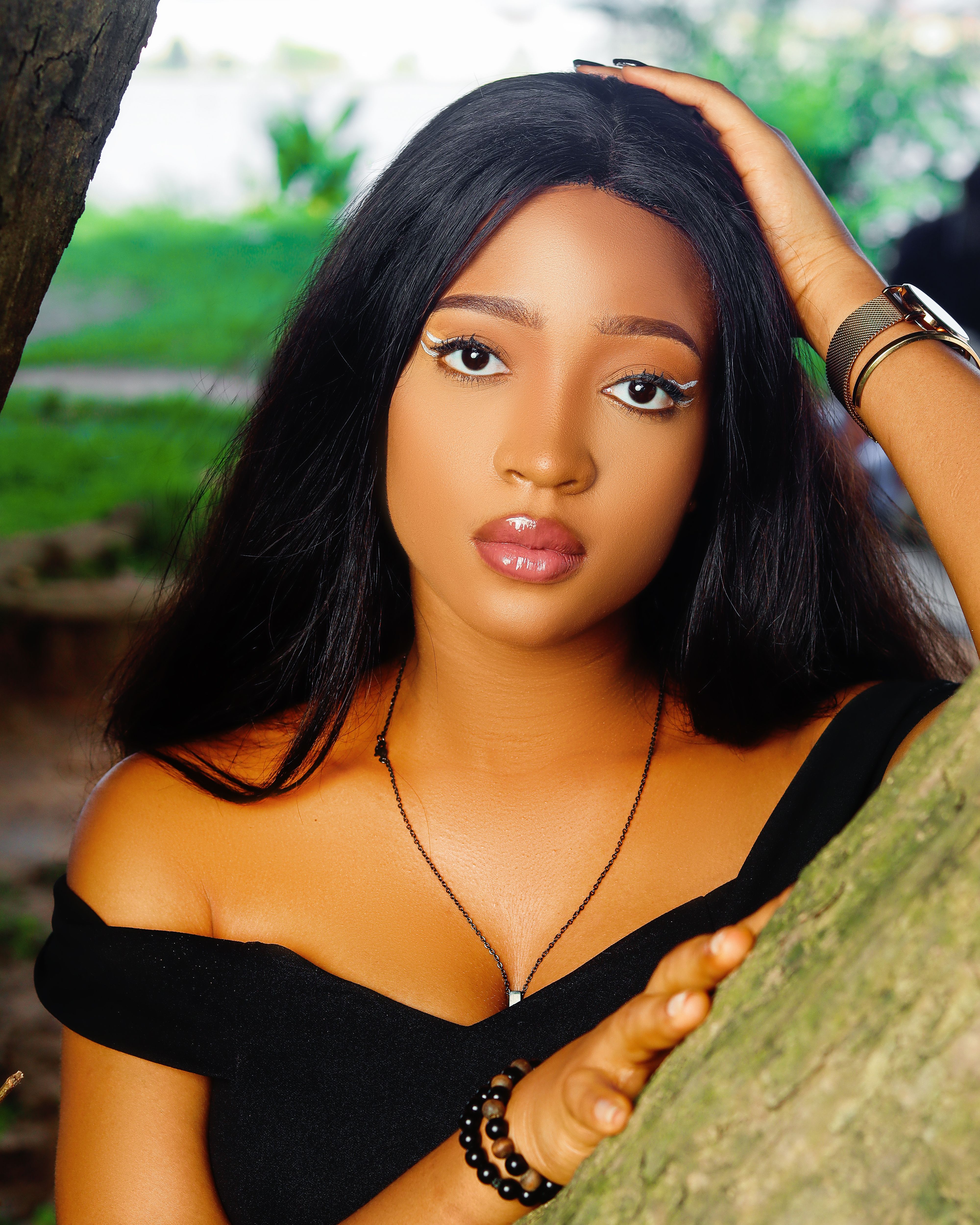 Stunning portrait of a young woman with makeup posing elegantly outdoors.