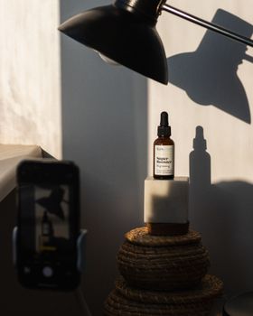 Elegant skincare bottle with dropper in sunlight and artistic shadows.