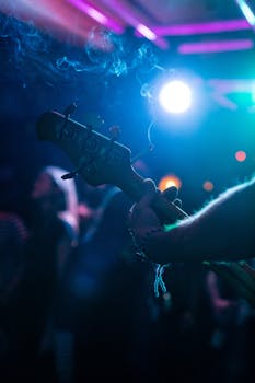 Guitarist performing in a dimly lit club with smoke and vibrant lights in Stuttgart.