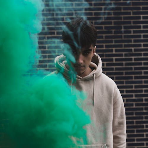 Young Man in White Hoodie Behind Green Smoke