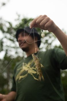 A man enjoys fishing in Natividade da Serra, SP, Brasil, holding a tiny fish.