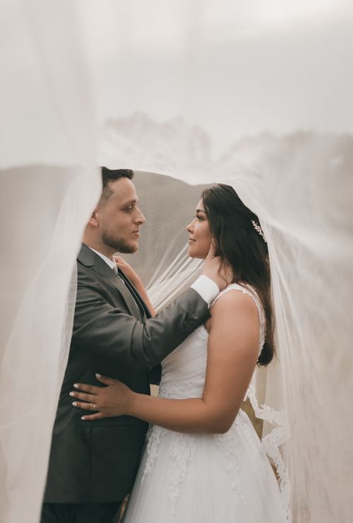 Free A loving couple embraces under a flowing veil on their wedding day, capturing intimate moments. Stock Photo