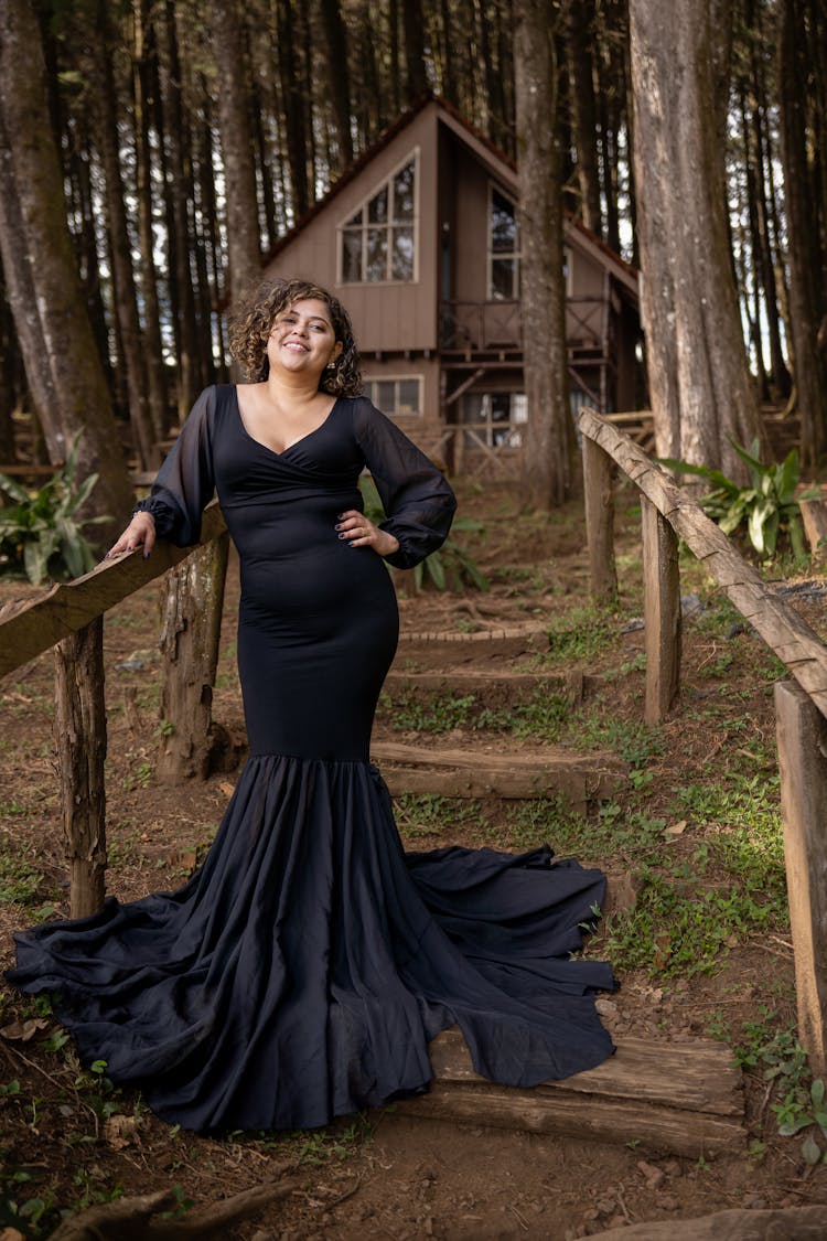 Woman In A Long Dress Standing On Steps In Front Of A House In Woods 