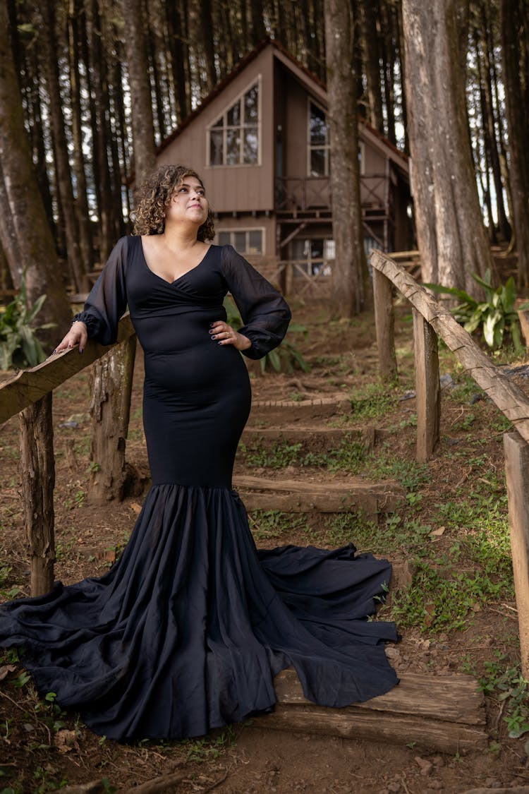 Woman In A Long Dress Standing On Steps In Front Of A House In Woods 